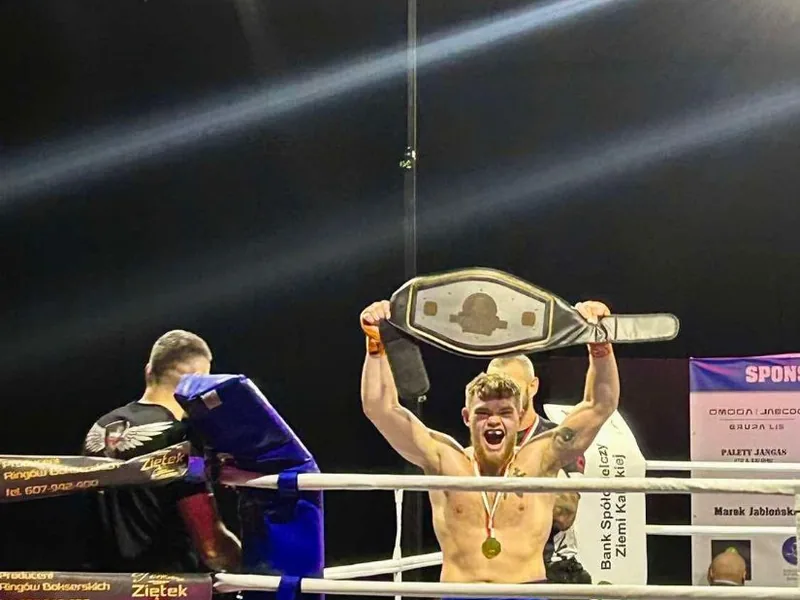 Janek Matyjaszczyk unosi nad głową pas mistrzowski na ringu